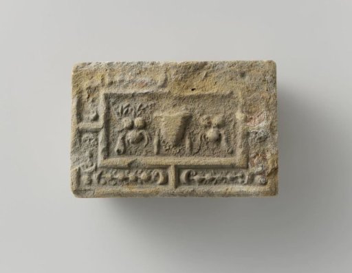 Fireplace surround with a representation of a mask between two fruit festoons