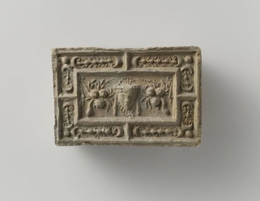 Fireplace surround with a representation of a mask between two fruit festoons