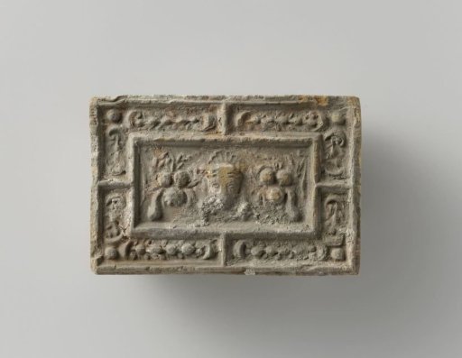 Fireplace stone with a representation of a mask between two fruit festoons