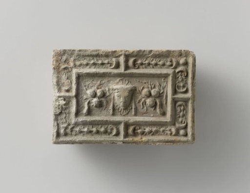 Fireplace stone with a representation of a mask between two fruit festoons