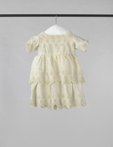 Children's dress with short sleeves and a fastening of three mother-of-pearl buttons of white cotton with English embroidery of flower and leaf sprigs; the skirt consists of two layers