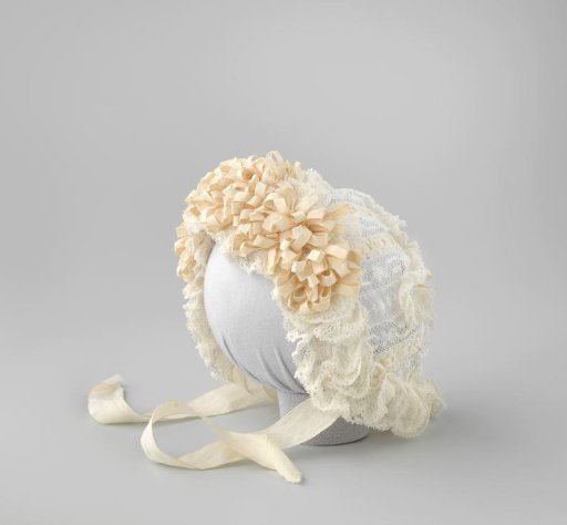 White lace cap, threaded with cream narrow satin ribbon and trimmed along the edge with tassels of ribbon