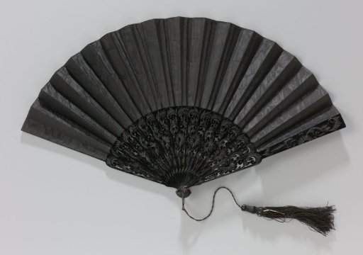 Folding fan with unadorned leaf of black moiré silk on pierced and relief-carved mount of black lacquered wood