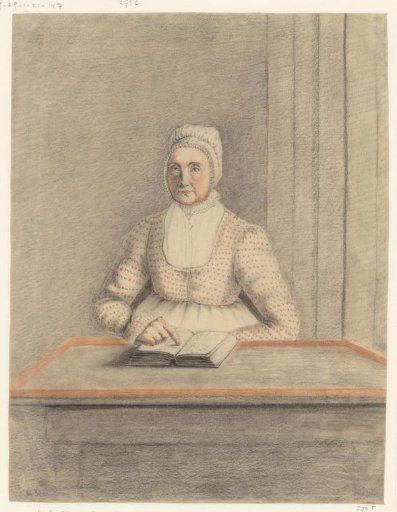 Seated woman at a table with open book