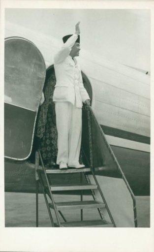 President Soekarno waves laughing from the steps of an aircraft