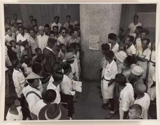 Indonesians reading a poster of the Partai Nasional Indonesia in Batavia