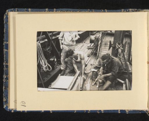 Sailors on board their ship with a dog
