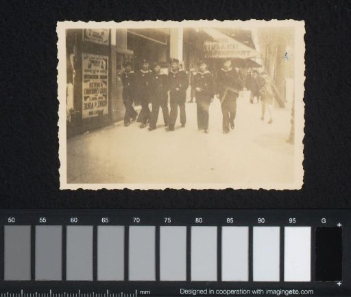 Six sailors walking through a shopping street