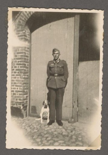Portrait of a Soldier in Uniform with a Dog in Front of a Door