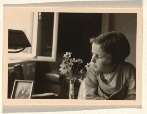 Isabel Wachenheimer seated next to flowers and looking at a photograph of her grandfather Meir Wachenheimer