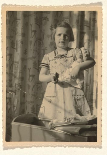 Isabel Wachenheimer in front of a pram and holding a doll in her arms, April-May 1935, Stuttgart