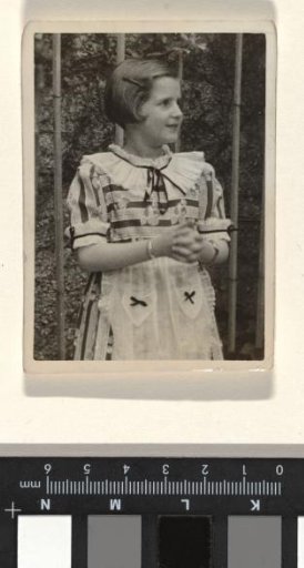 Isabel Wachenheimer in a striped dress in front of a fence on Evi's birthday, May-June 1937