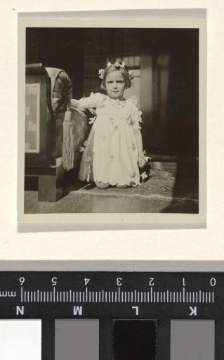 Isabel Wachenheimer with a flower wreath and flower necklace, kneeling by a bench