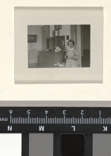 Isabel Wachenheimer in a striped dress with a wreath in her hair in front of a cabinet