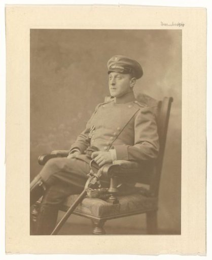 Arthur Moos with a sabre in the uniform of the German Army, with the Iron Cross on his chest, seated on a chair, December 1914