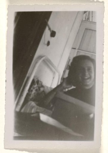 Isabel Wachenheimer smiling and lying in a hospital bed with her head resting on her arm in the sanatorium Etania in Davos, 12 August 1945