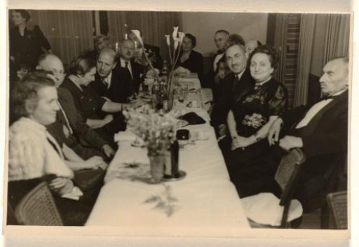 Row of Unknown People in Festive Clothing Seated at a Table