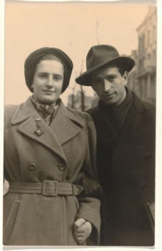 Isabel Wachenheimer in a long coat with Leo Blumensohn wearing a slit hat on the street in Amsterdam, May 1947