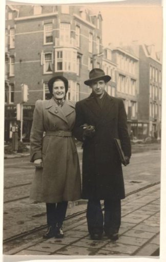 Isabel Wachenheimer in a long coat with Leo Blumensohn wearing a slit hat on the street in Amsterdam, May 1947
