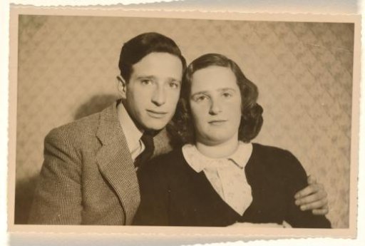 Leo Blumensohn in a striped jacket with his arm around Isabel Wachenheimer, in front of a diamond-patterned wallpaper, both with serious expressions, 1945