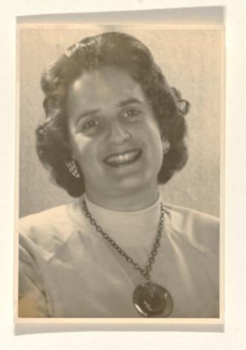 Isabel Wachenheimer with a turtleneck and a necklace with musical notes around her neck, smiling and looking forward
