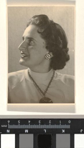 Isabel Wachenheimer with a turtleneck and a necklace with musical notes around her neck, smiling and looking to the left