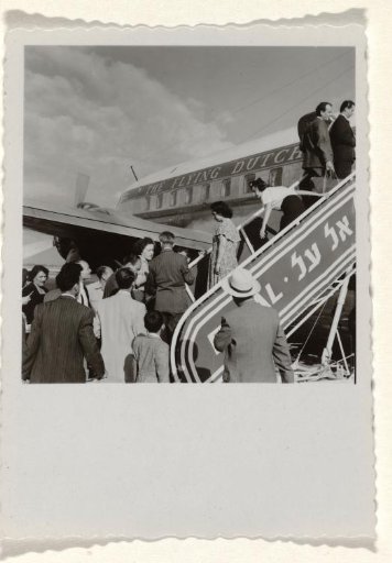 Isabel Wachenheimer standing on the stairs of the KLM aircraft The Flying Dutchman with ground staff and passengers, with Hebrew letters on the stairs