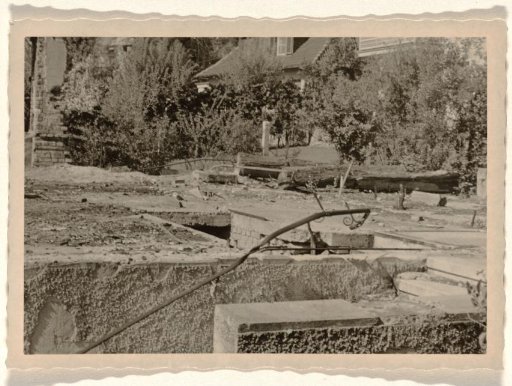 Top part of a section of a ruin, with a house surrounded by trees in the background