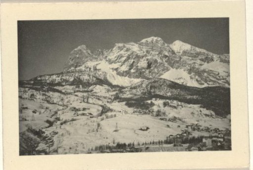 Snowy mountain landscape with trees and buildings in the foreground