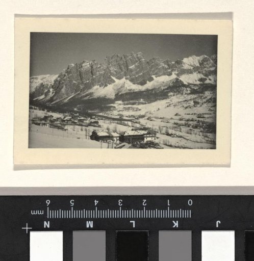 Snowy mountain landscape with trees and buildings in the foreground