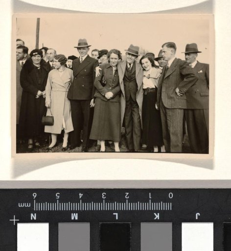 Group of unknown men and women in a row, including three men with slit hats and a man with a slit hat with his arm around a woman