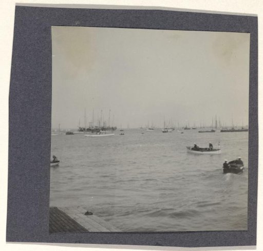 View of sailing ships, including a large ship with five masts in the background and two smaller boats in the foreground, with part of a quay or pier in the foreground