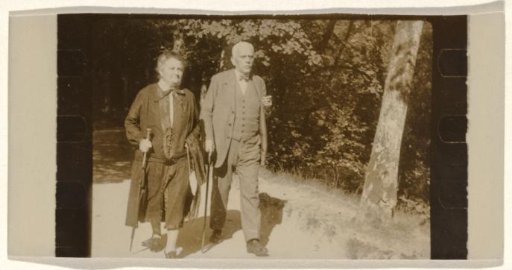 Meir Wachenheimer and his wife Mathilde Wachenheimer-Wertheimer, both holding walking sticks, walking along a forest path with trees and grass