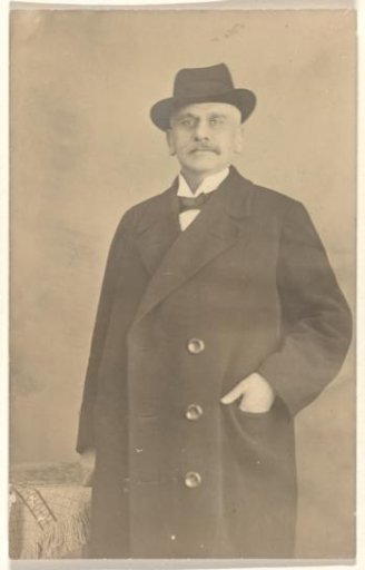 Portrait of Meir Wachenheimer, with a hat on his head and hand in the jacket pocket of a three-button coat