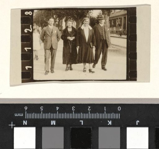 Willy Moos, Josefine Moos-Levi and two unknown persons walking on the street, with trees and a building in the background