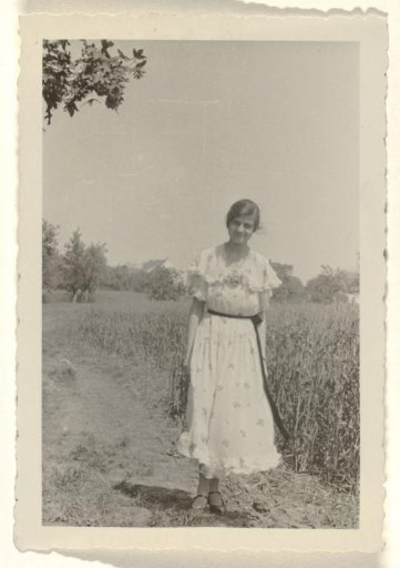Member of the household staff of the Wachenheimer family, possibly the nursemaid, in a spotted dress standing beside a field