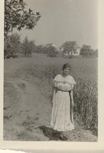 Member of the household staff of the Wachenheimer family, possibly the nursemaid, in a spotted dress standing beside a field
