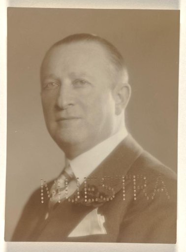 Portrait of Willy Moos, with a sword belt on his chest and the text Muestra printed on the front