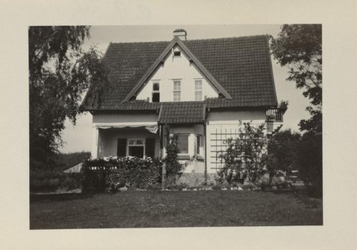 House Fahrenkamp, with a white triangular extension on the roof and a rose trellis on the right side of the house