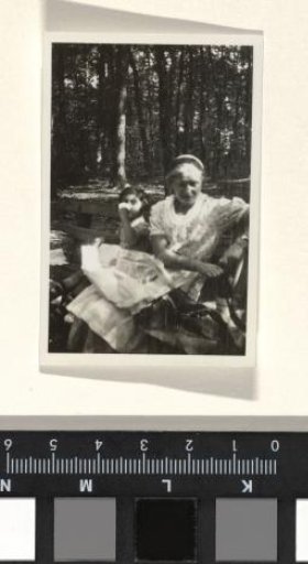 Unknown Woman with a Bag on Her Lap and a Child Sitting on a Bench in a Wooded Environment