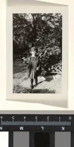 Child in a Garden with a Fence in the Background, Holding Flowers and Dressed in Dark Clothing, During Whitsun 1933