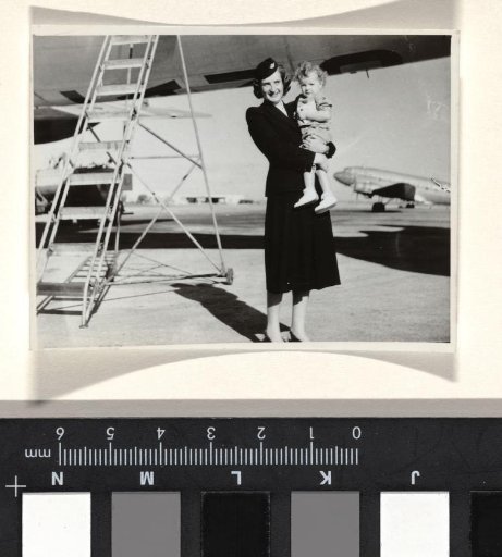 Isabel Wachenheimer in KLM uniform with a child on her arm, standing in front of a KLM aircraft with a ladder against it