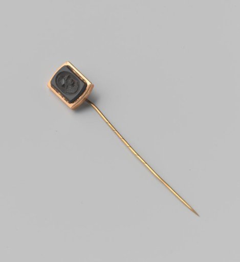 Black stone with the engraved bust of a man, set in a rectangular holder attached to a pin