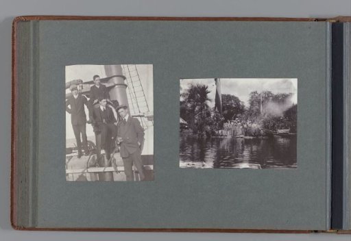 Group of Surinamese (?) standing between two flags, viewed from the water