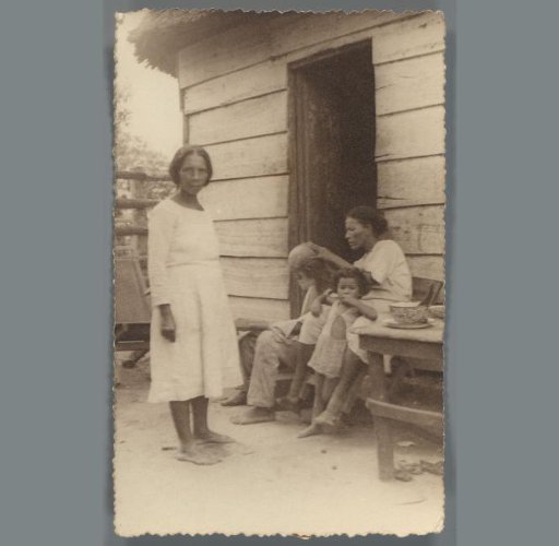 Group portrait of two women, a man and a child in front of their house