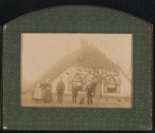 Five persons and a dog in front of a house