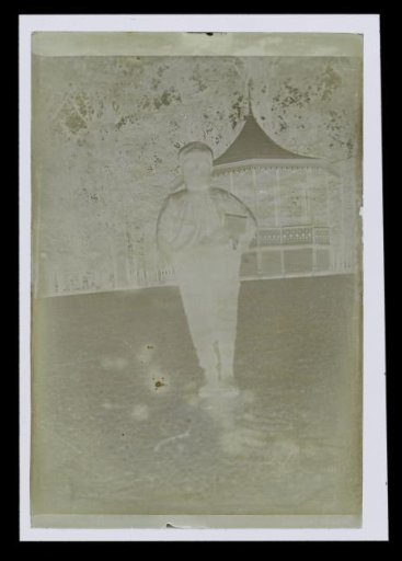 Portrait of an unknown boy on a grassy field, with a music tent in the background