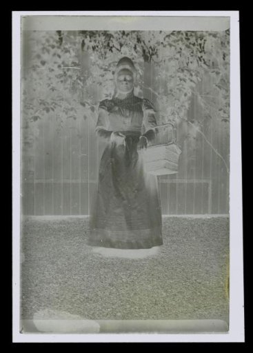 Portrait of an unknown woman with a basket on her arm, standing in a garden