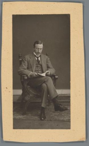 Studio portrait of H.J. de Lange, reading in a chair