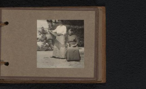 Two women with a newspaper in a garden